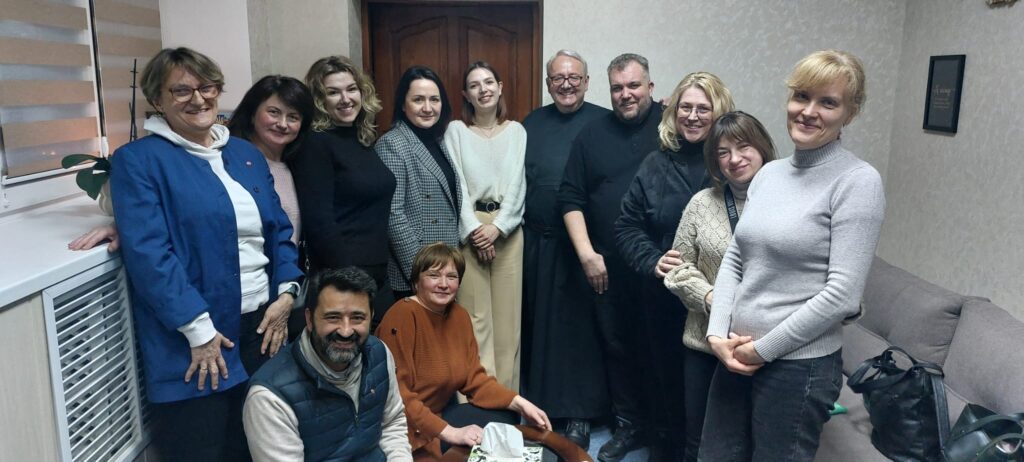 El padre Anton y Magda Kaczmarek junto a un grupo de mujeres que han perdido un marido o un hijo, o ambos, en la guerra de Ucrania.